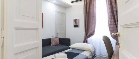 A bedroom with two beds, a desk, and a chair.