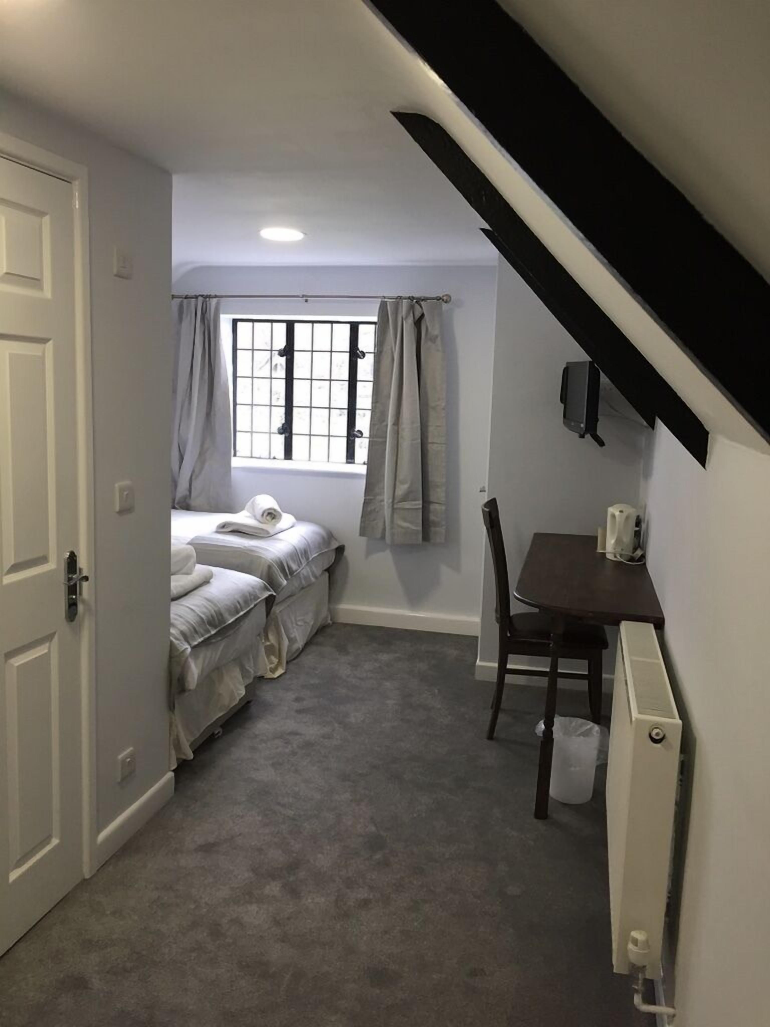 A compact room with a bed, a desk, and a radiator.