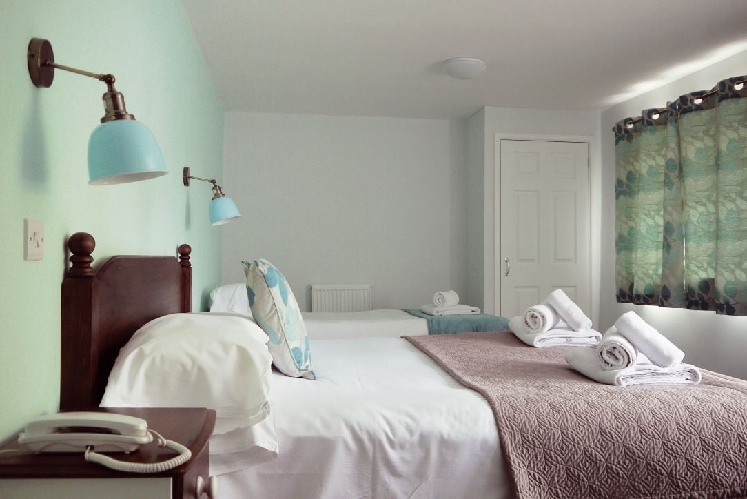 A hotel room with two beds, a telephone, and a window with curtains.