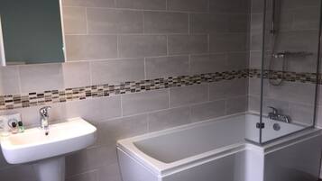 Une salle de bain avec un lavabo blanc, une baignoire et une douche.