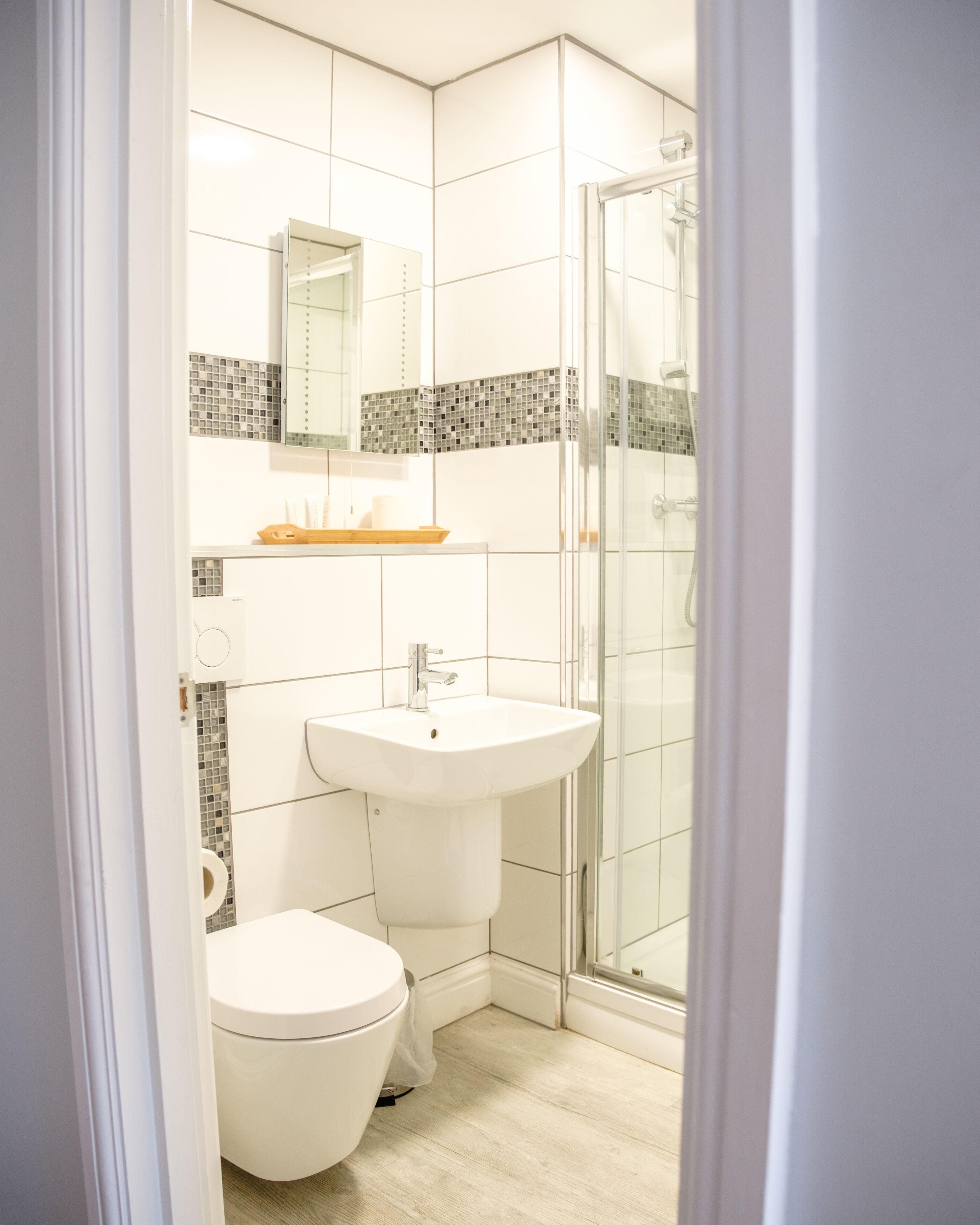 Un baño con inodoro, lavamanos y cabina de ducha de vidrio.