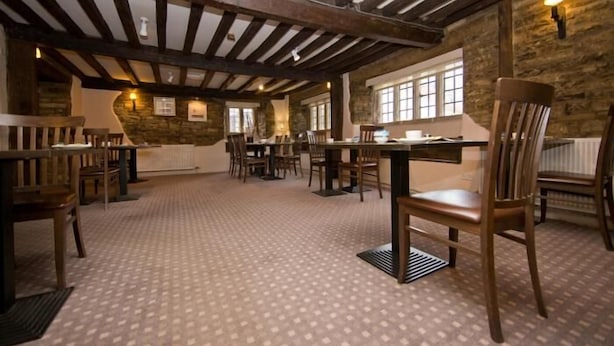 A spacious dining area with wooden beams, stone walls, and large windows.