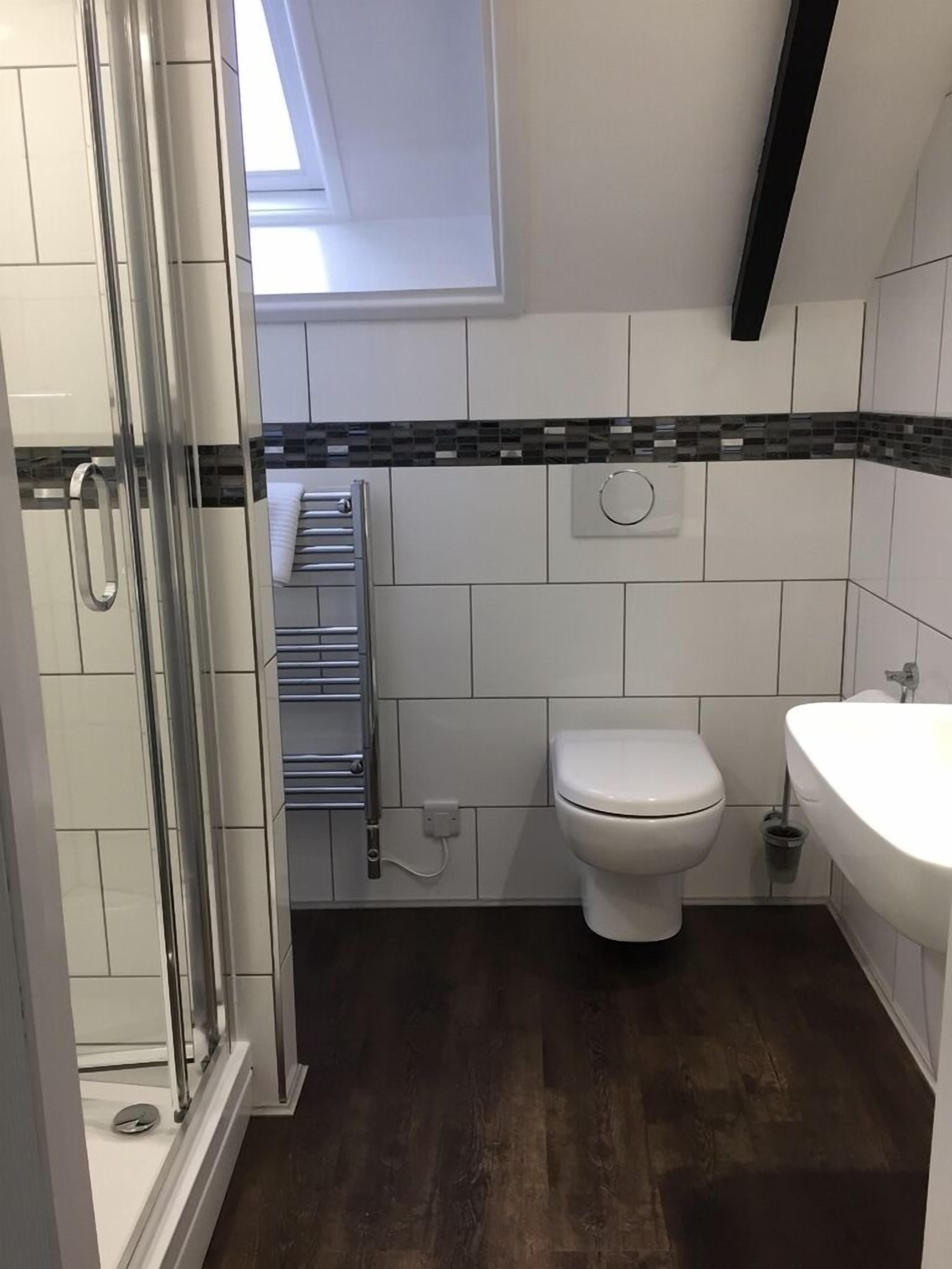 A modern bathroom with a glass shower enclosure, a toilet, and a sink.