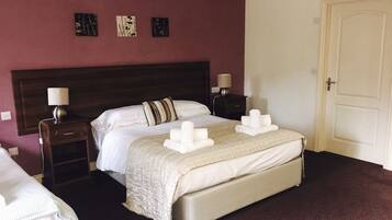 A hotel room with a large bed, two bedside tables with lamps, a door, and a wall with three framed pictures.