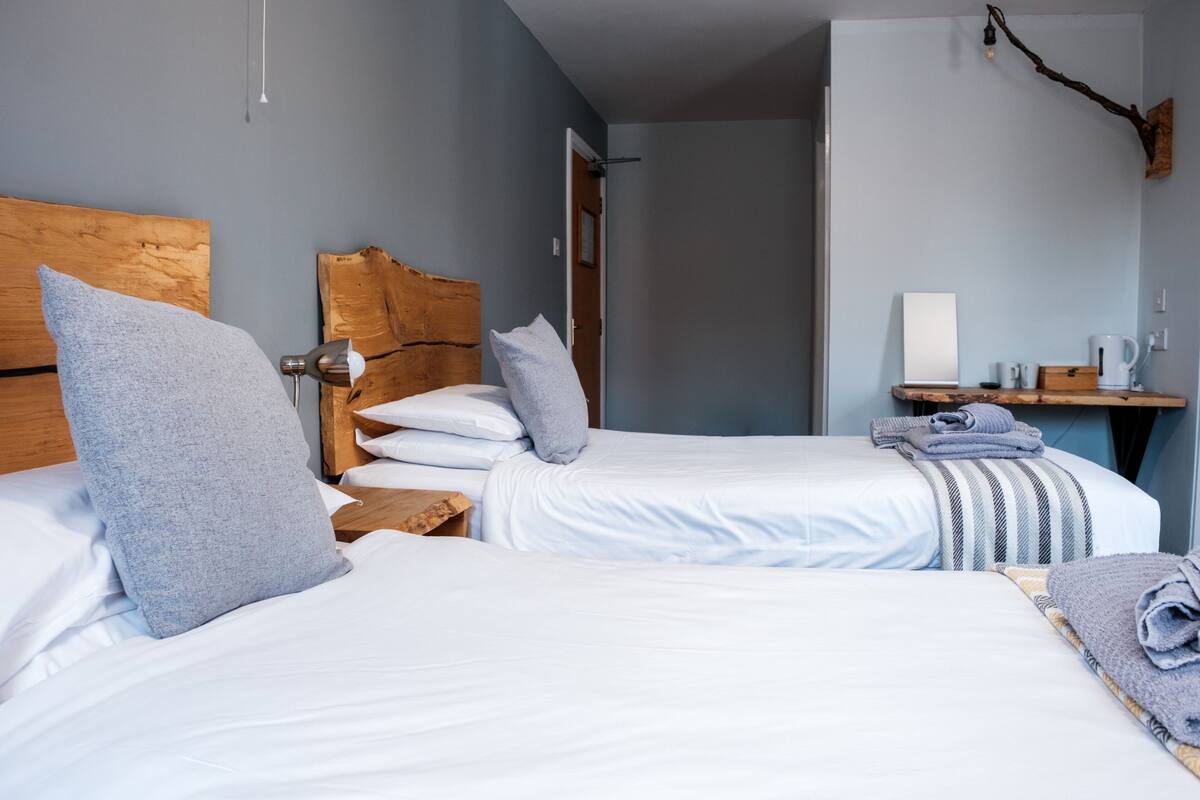 A hotel room with two beds, wooden headboards, and a small desk with a coffee maker.