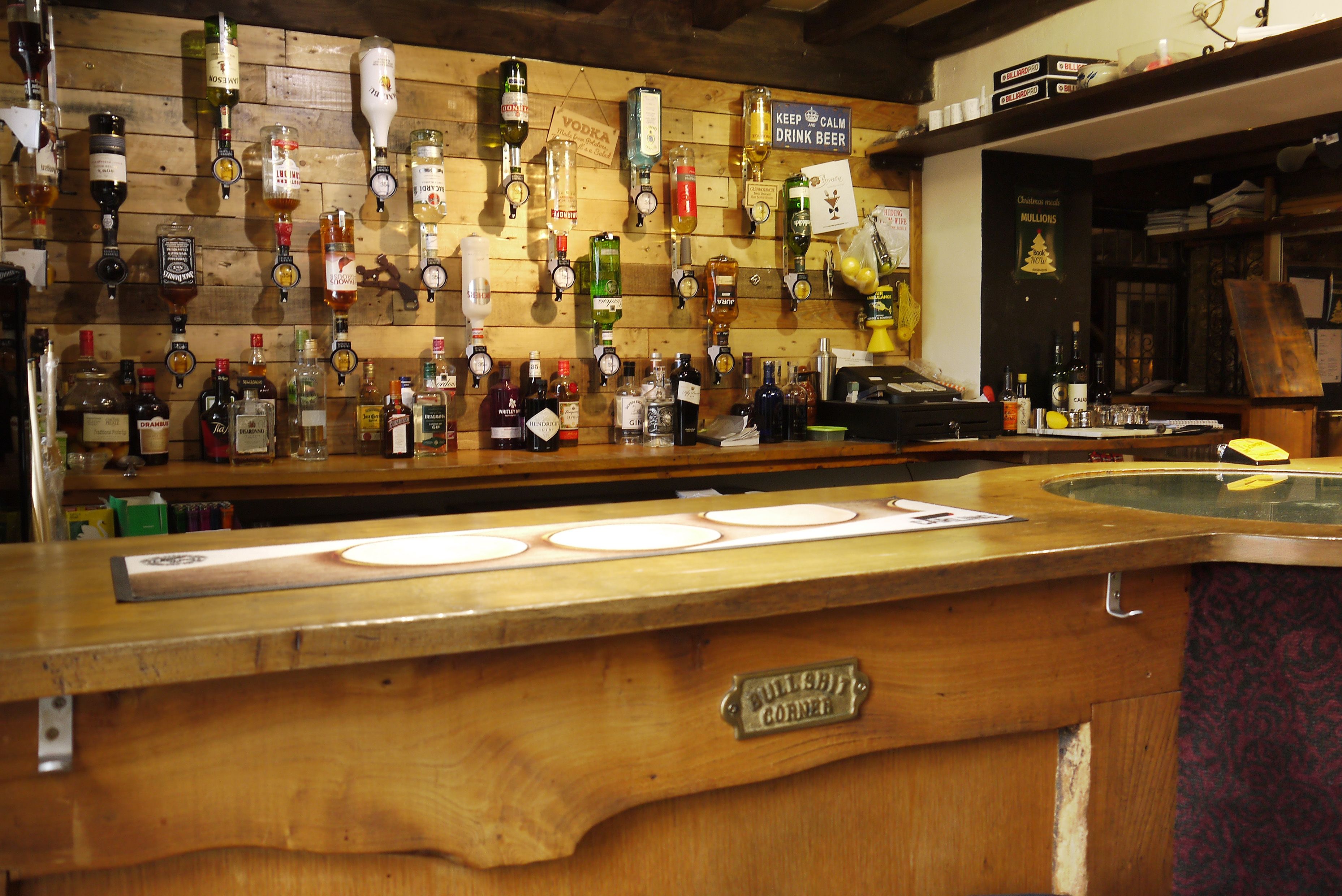 Zona de bar con varios dispensadores de licores y una barra de madera.