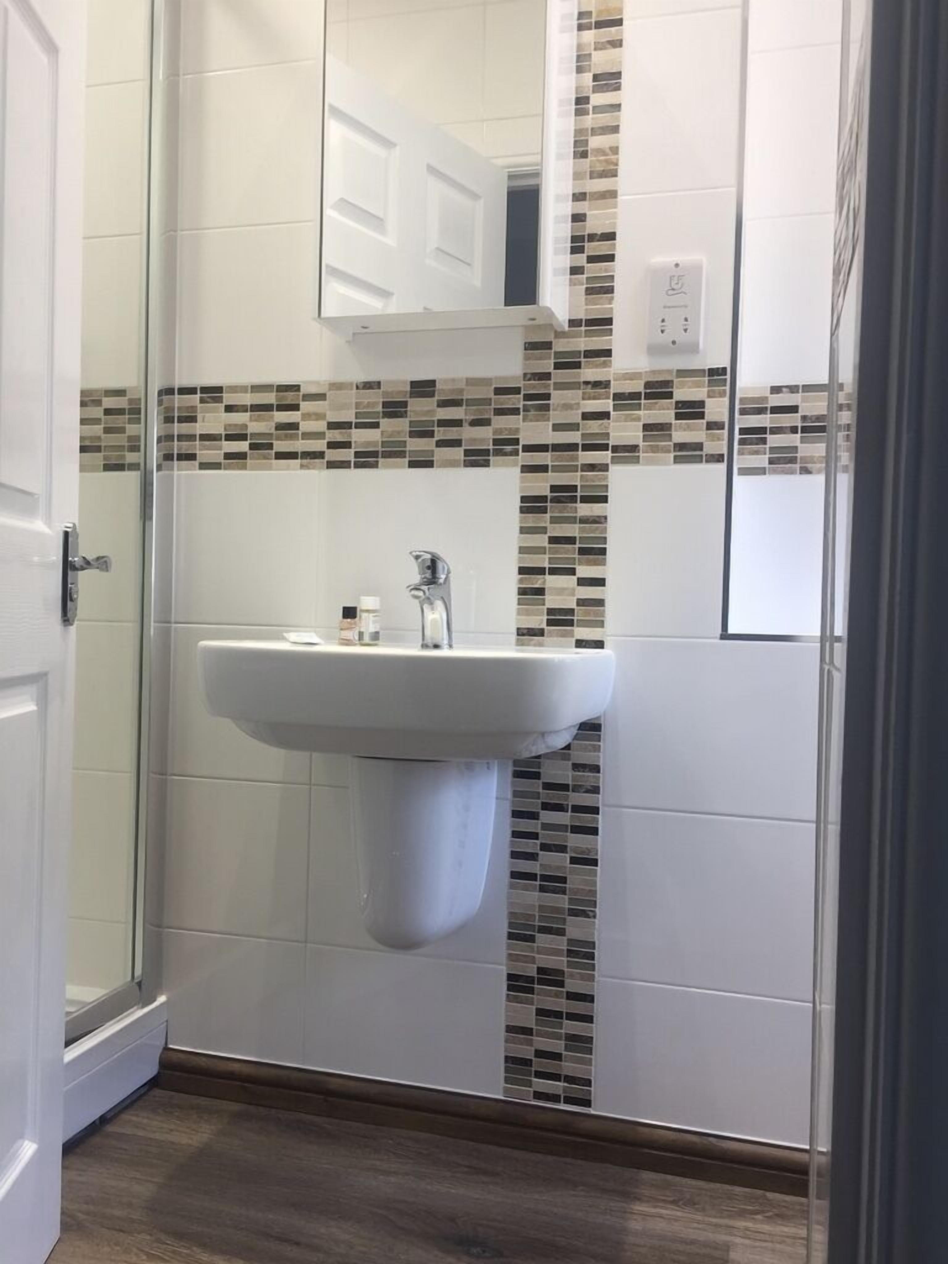 A bathroom with a white sink, a mirror, and a tiled backsplash.