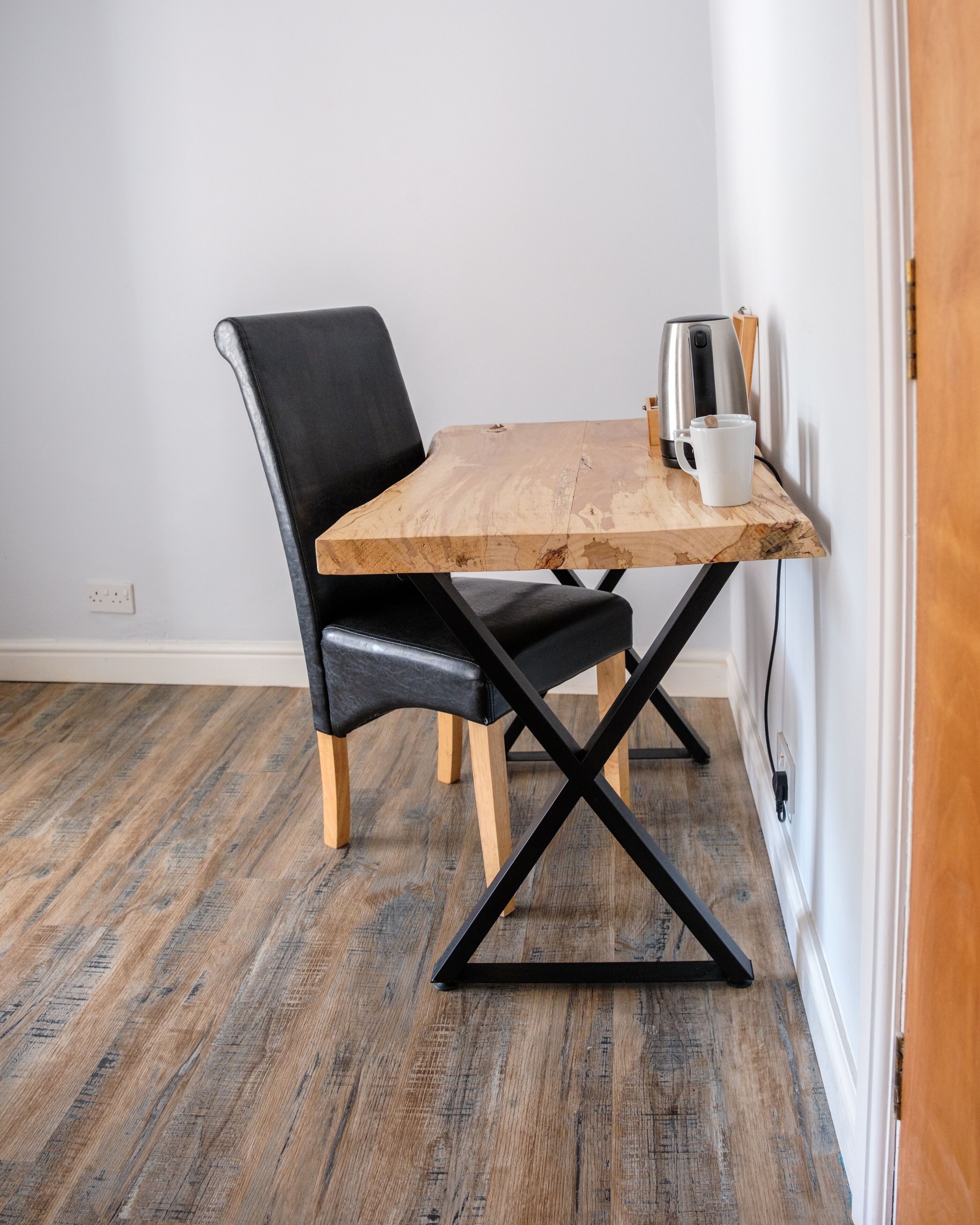 A dining table with a wooden top and black metal legs, accompanied by two black leather chairs.