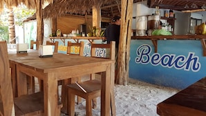 Un restaurant à thème balnéaire, avec des meubles en bois et un toit de chaume.