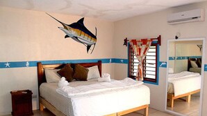 Une chambre à coucher comprenant un lit, un miroir, un climatiseur fixé au mur et une fresque murale décorative représentant des poissons.
