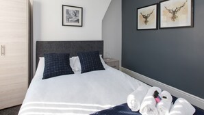 Een moderne hotelkamer met een groot bed, een kledingkast en twee ingelijste foto’s aan de muur.