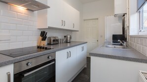 Een moderne keuken met witte kasten, een inbouwoven, een roestvrijstalen afzuigkap en een granieten aanrecht.