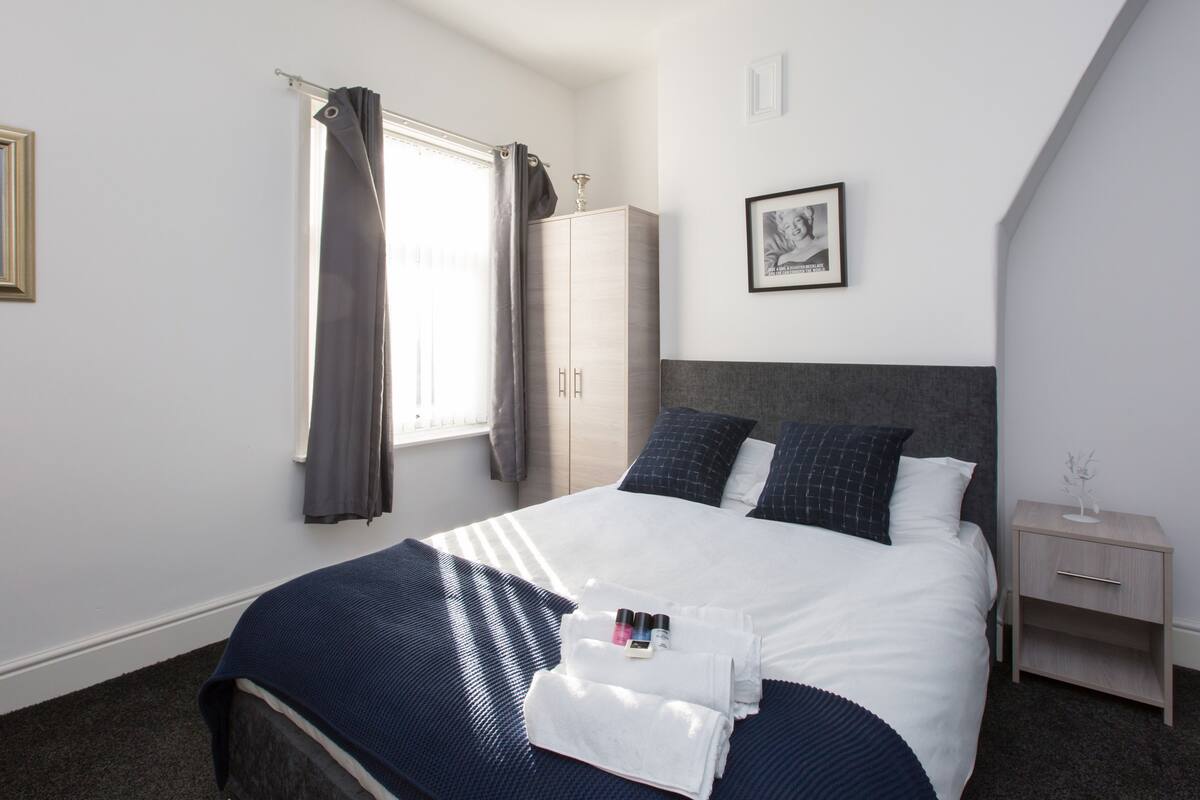 Une chambre à coucher bien rangée, avec un lit, une table de chevet, une armoire et un tableau encadré au mur.