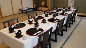 A traditional Japanese-style dining room with tatami mats, low tables, and black and white tableware. - KKR Kawayu (Teshikaga)