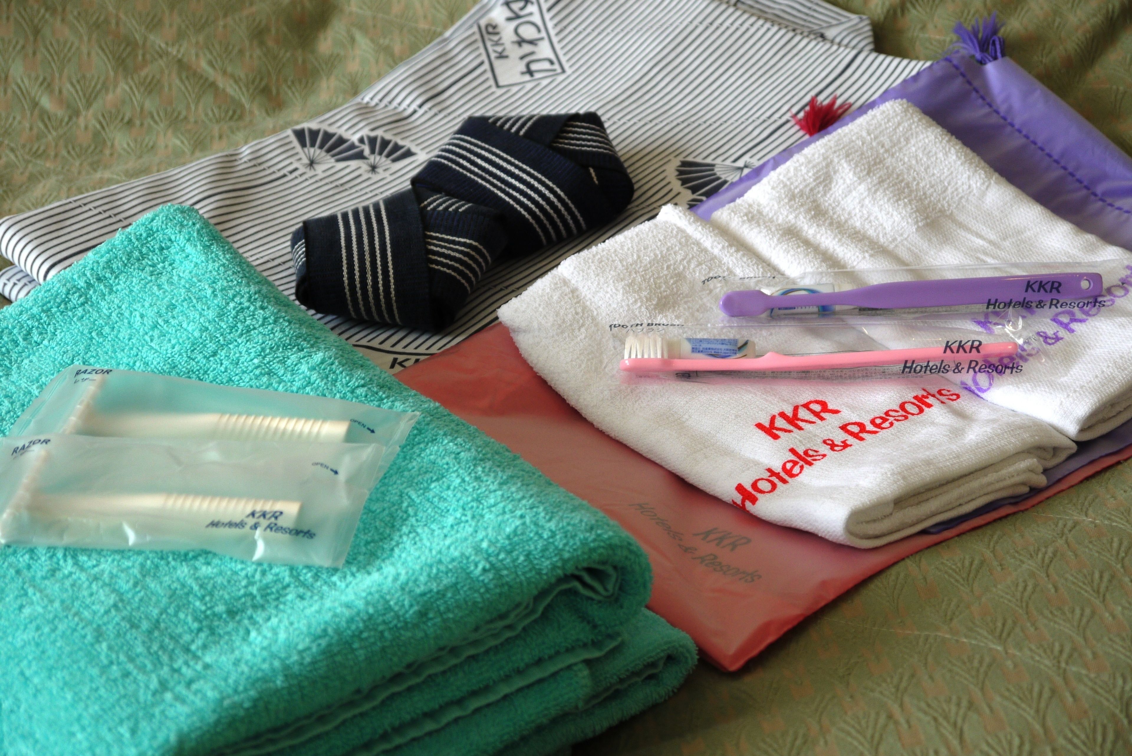 A neatly arranged set of toiletries and towels on a bed with a patterned bedspread.