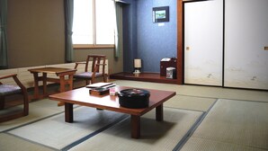 A traditional Japanese room with tatami flooring, a low wooden table, two chairs, a cabinet with a lamp, and a sliding door. - KKR Kawayu (Teshikaga)