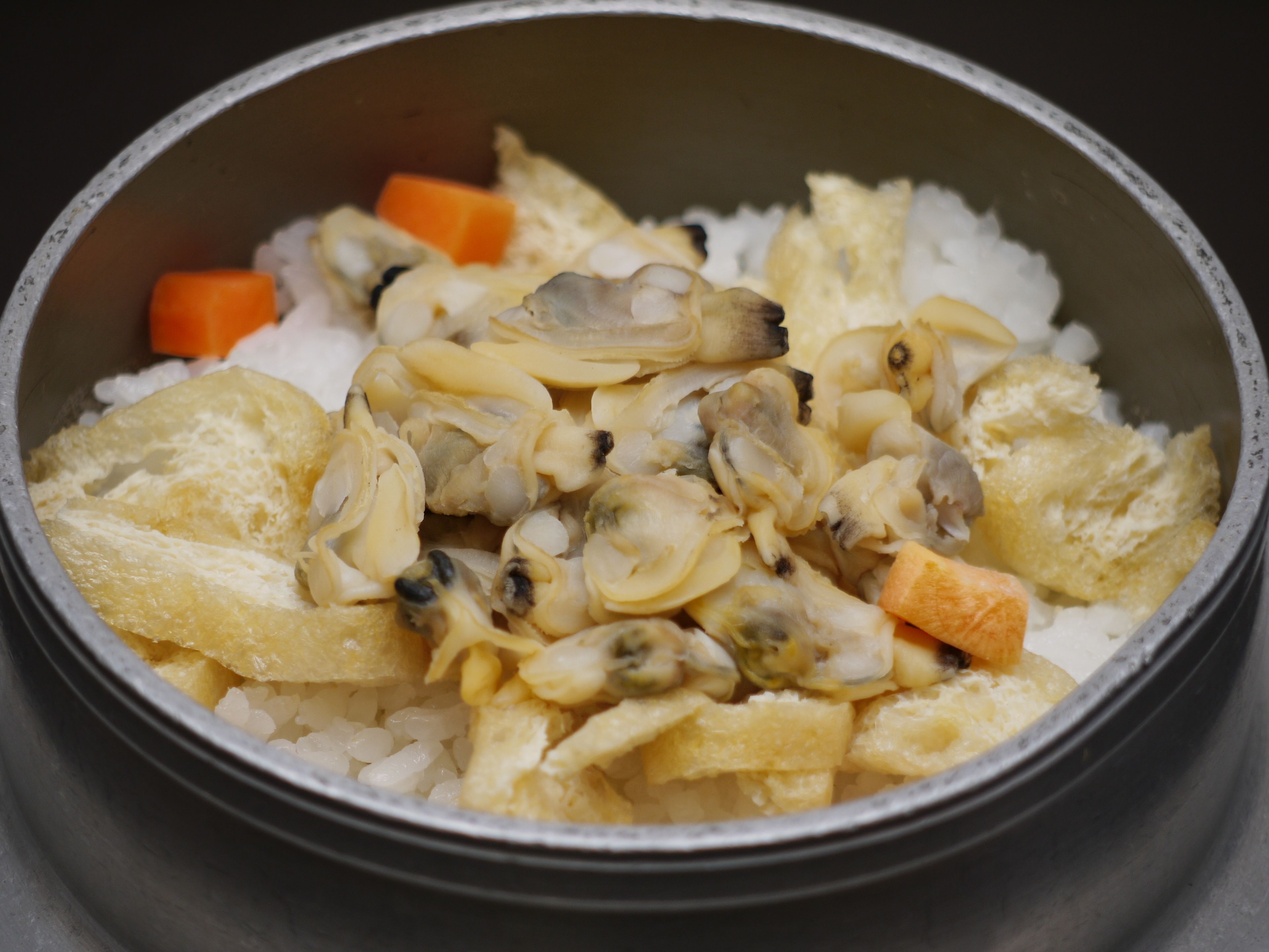 A bowl containing rice, mushrooms, and carrot pieces.