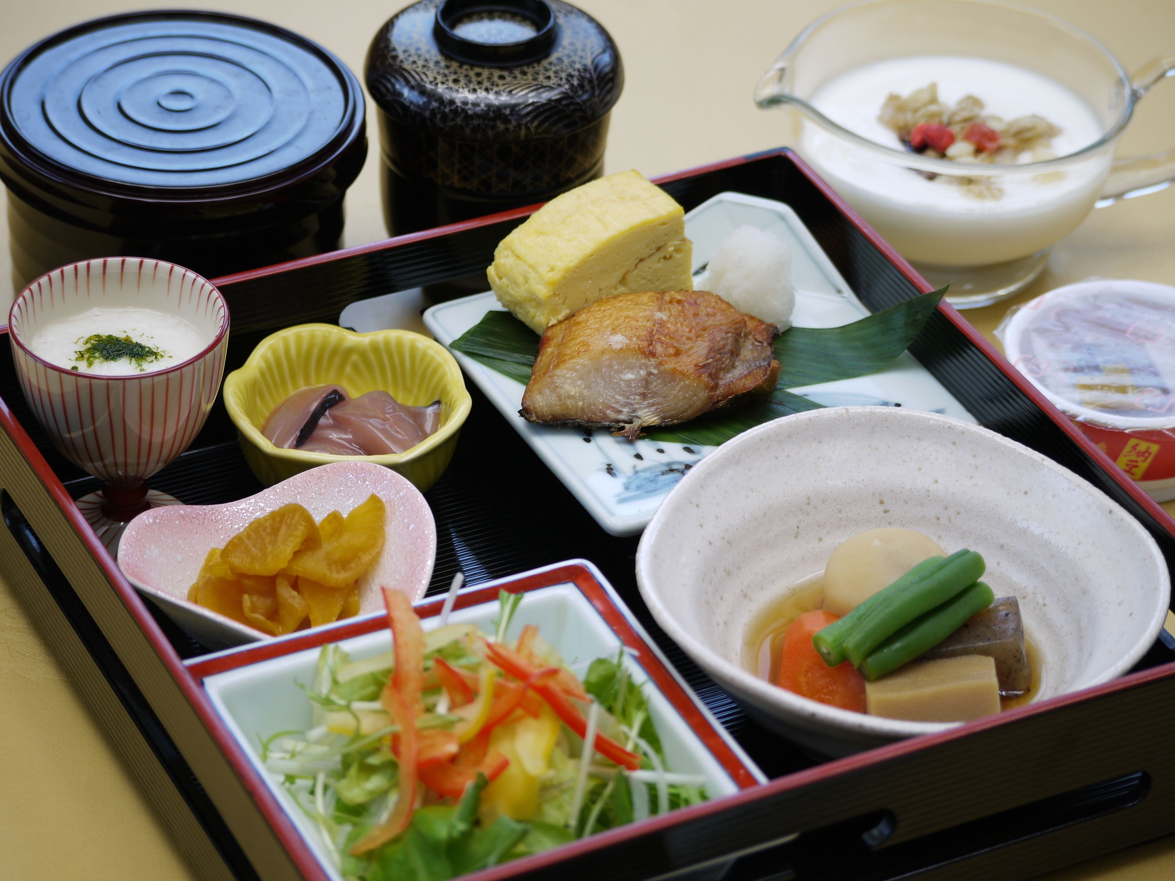A traditional Japanese bento box with various food items including fish, vegetables, and rice.