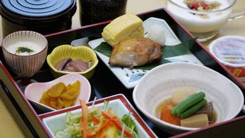 A traditional Japanese bento box with various food items including fish, vegetables, and rice.