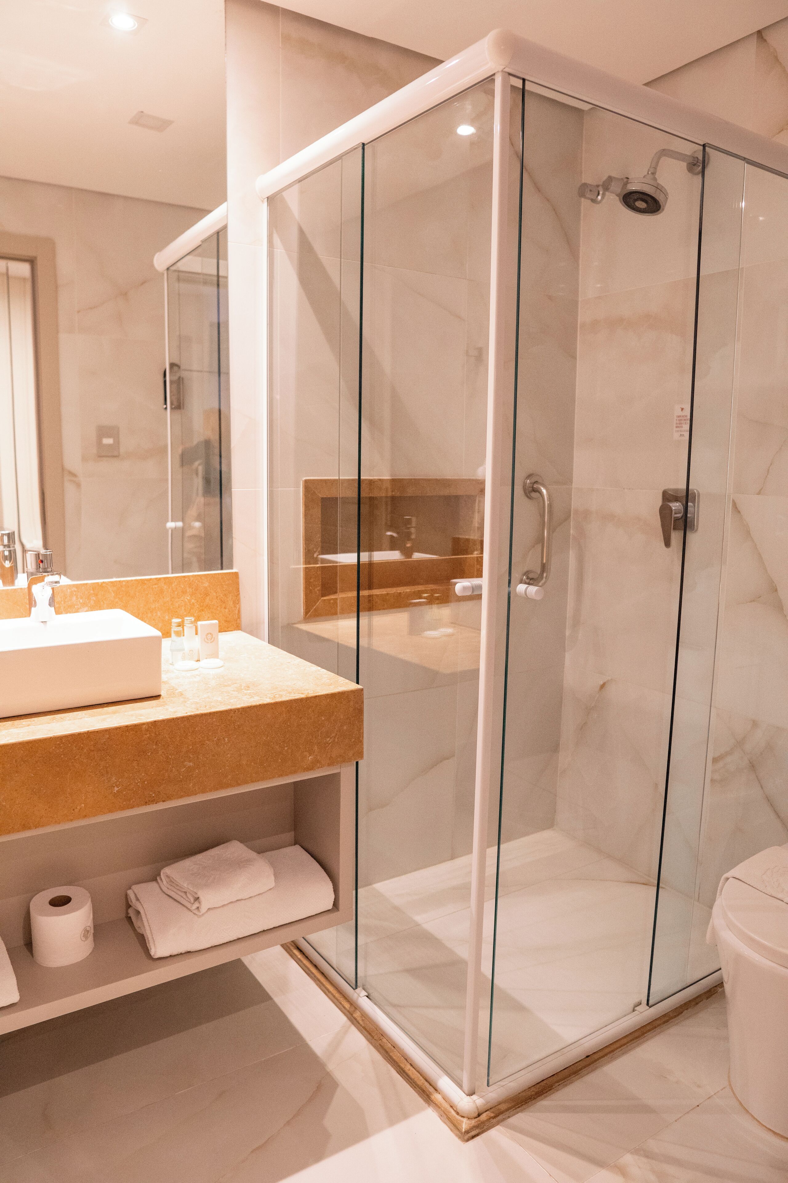 A modern bathroom with a glass-enclosed shower, a vanity with a sink, and a mirror.