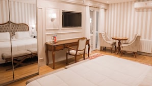 A hotel room with a large bed, a desk with a chair, a small table with two chairs, a television, and a mirror. - Daara Transamerica Collection Gramado (Gramado)