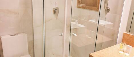 A modern bathroom with a glass-enclosed shower, a toilet, and a vanity with a mirror.