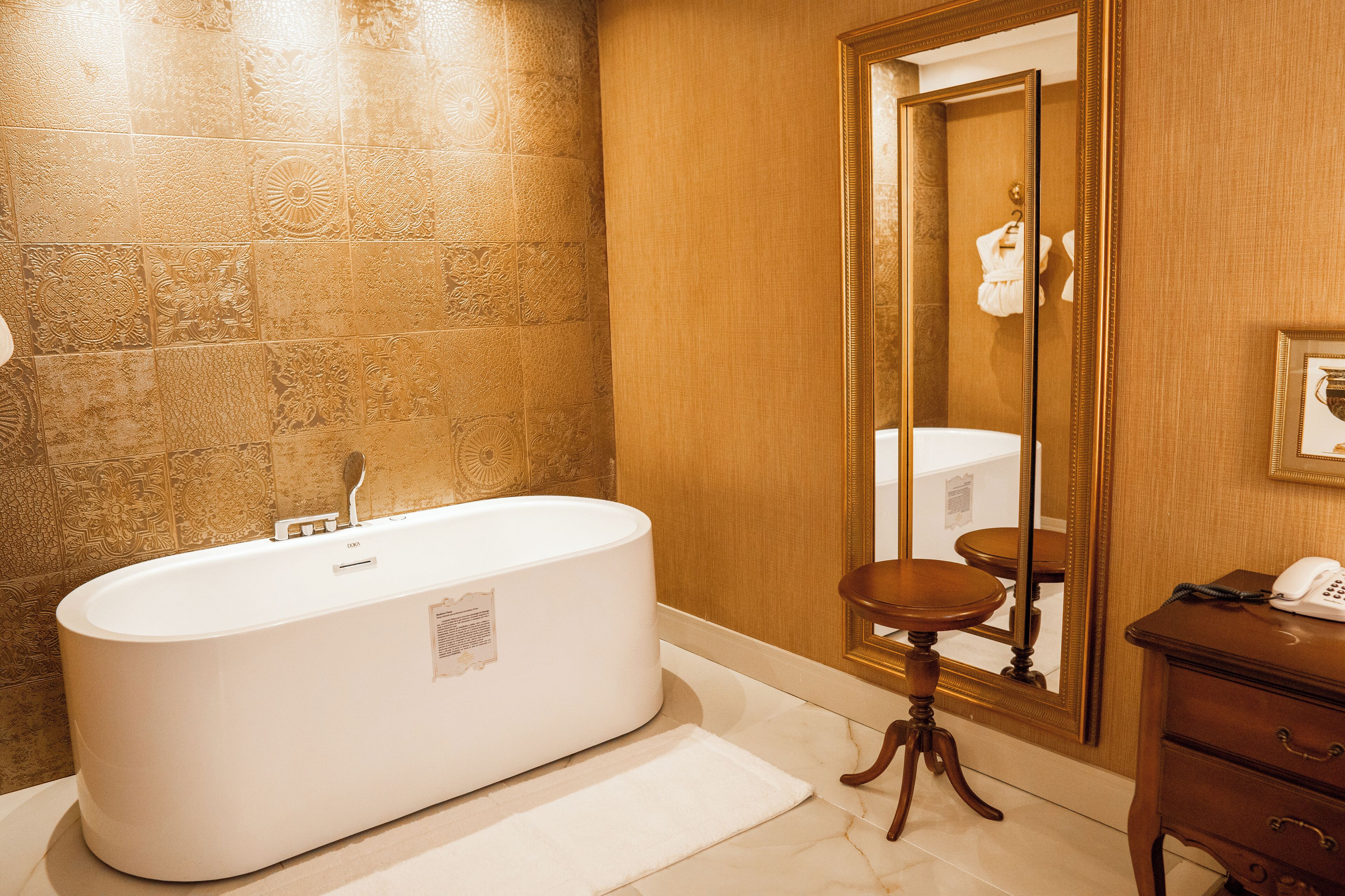 Un baño con una bañera independiente, un tocador de madera y un espejo grande.