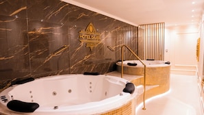 A luxurious bathroom with two large tubs, a marble wall, and a sign for Hotel Daara Gramado. - Daara Transamerica Collection Gramado (Gramado)