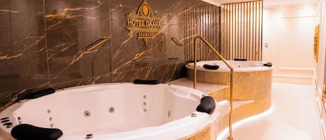 Un baño lujoso con dos bañeras grandes, una pared de mármol y un letrero del Hotel Daara Gramado.