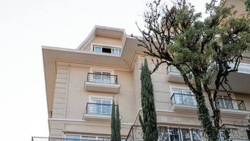 A multi-story hotel with balconies and a staircase leading to the entrance.