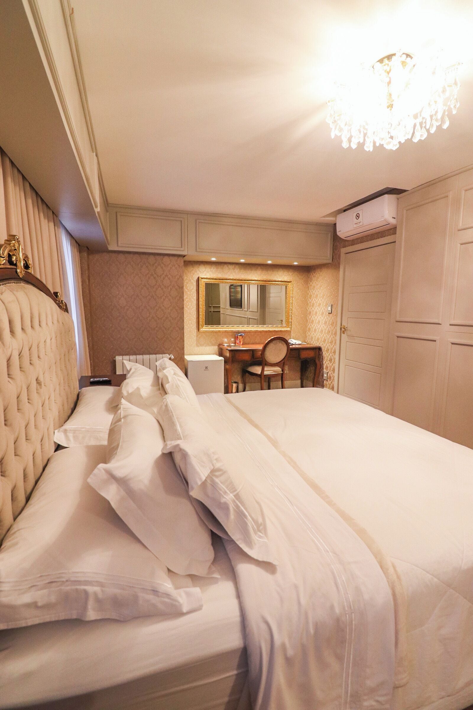 Une chambre d’hôtel avec un grand lit, un bureau, une chaise, un miroir et une armoire.