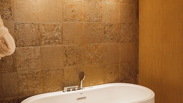 Un baño moderno con una bañera independiente, azulejos con diseño y luces empotradas en el techo.