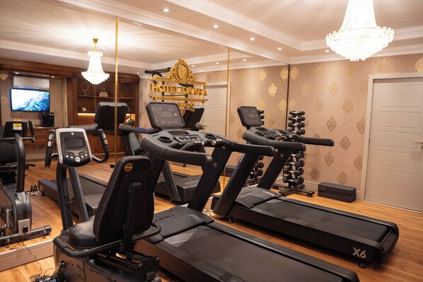 Una palestra alberghiera con tapis roulant, cyclette e una televisione.