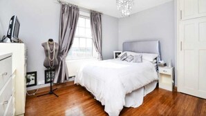 A bedroom with a large bed, a dresser, a vanity, and a chandelier. - Stylish 2 Bed Between Camden Town & Primrose Hill (London)