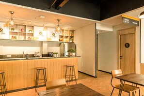 A modern kitchen with a wooden countertop, bar stools, and pendant lighting. There is a sign indicating the location of the restroom and elevator.