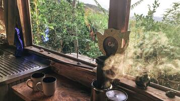 Una mesa de madera rústica con una cafetera, dos tazas y un letrero decorativo.
