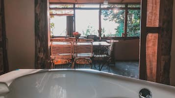 Un baño con bañera, una puerta de madera y una ventana con vistas al exterior.