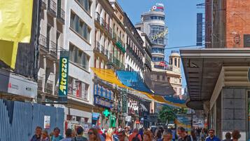 A busy urban street with pedestrians, shops, and a prominent building with a sign.