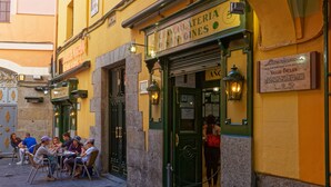 A café with outdoor seating, a green door, and a sign indicating it is a chocolate shop. - Arenal Suites (Madrid)