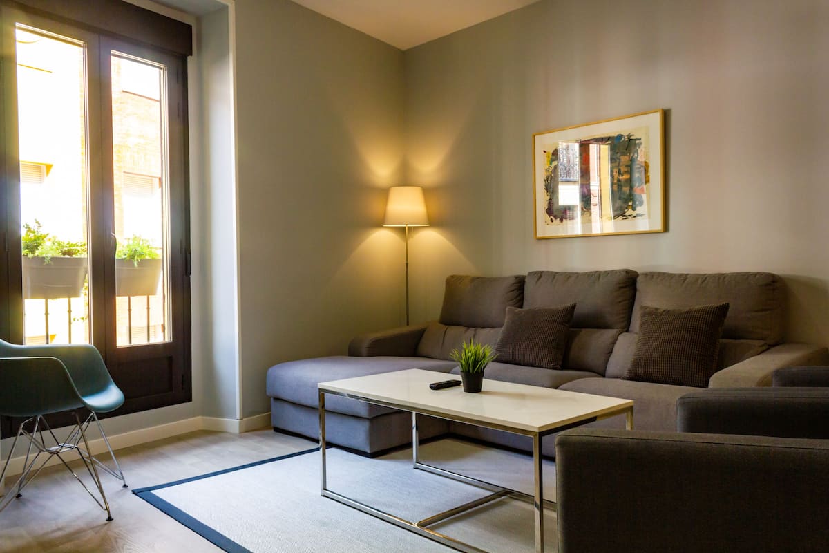 A modern living room with a sofa, a coffee table, a lamp, and a framed artwork on the wall.