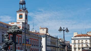 A historic building with a clock tower, a statue, and classic European architecture.