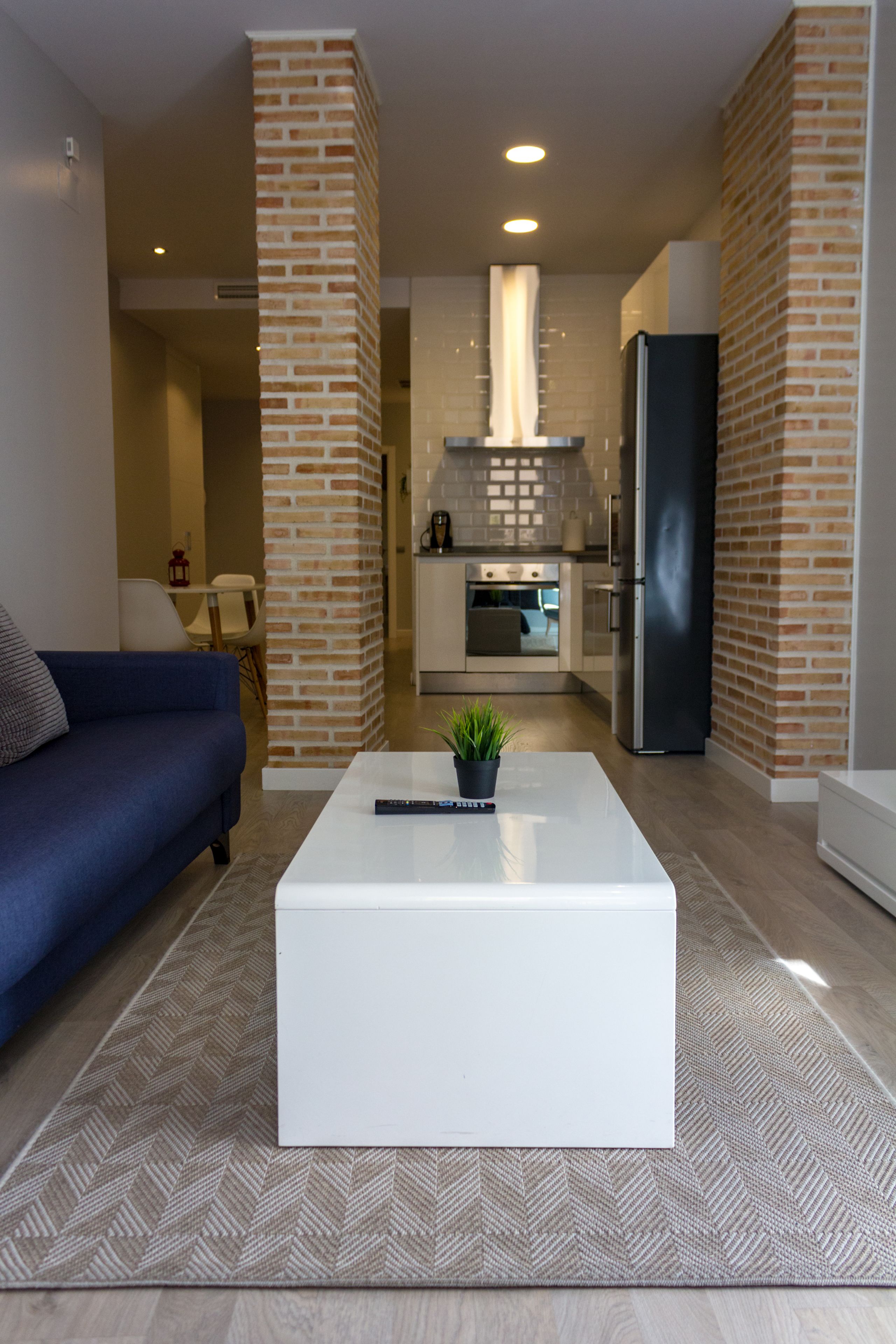 A modern living room with a sofa, a coffee table, and a kitchen in the background.