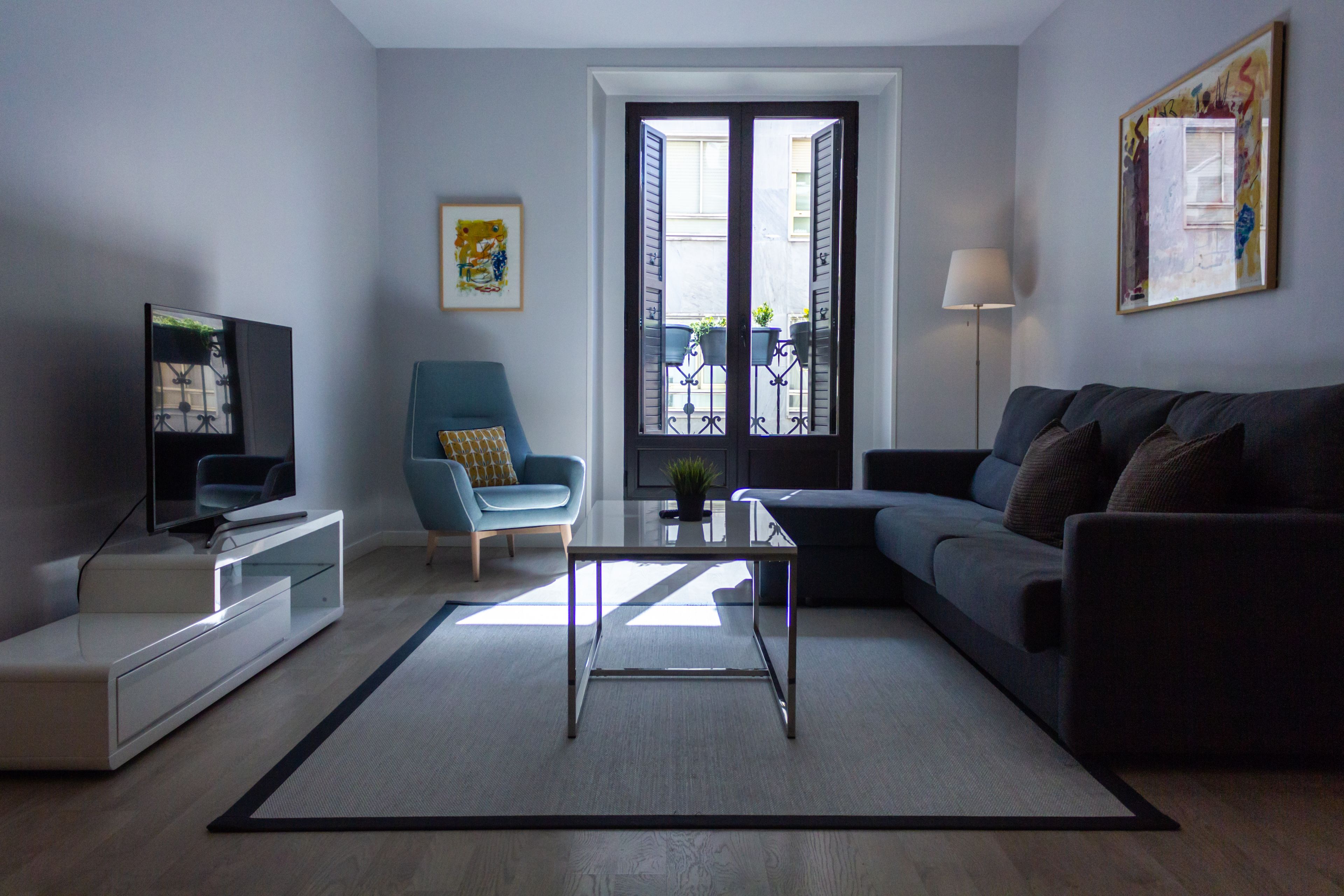 A modern living room with a sofa, armchair, coffee table, and TV.