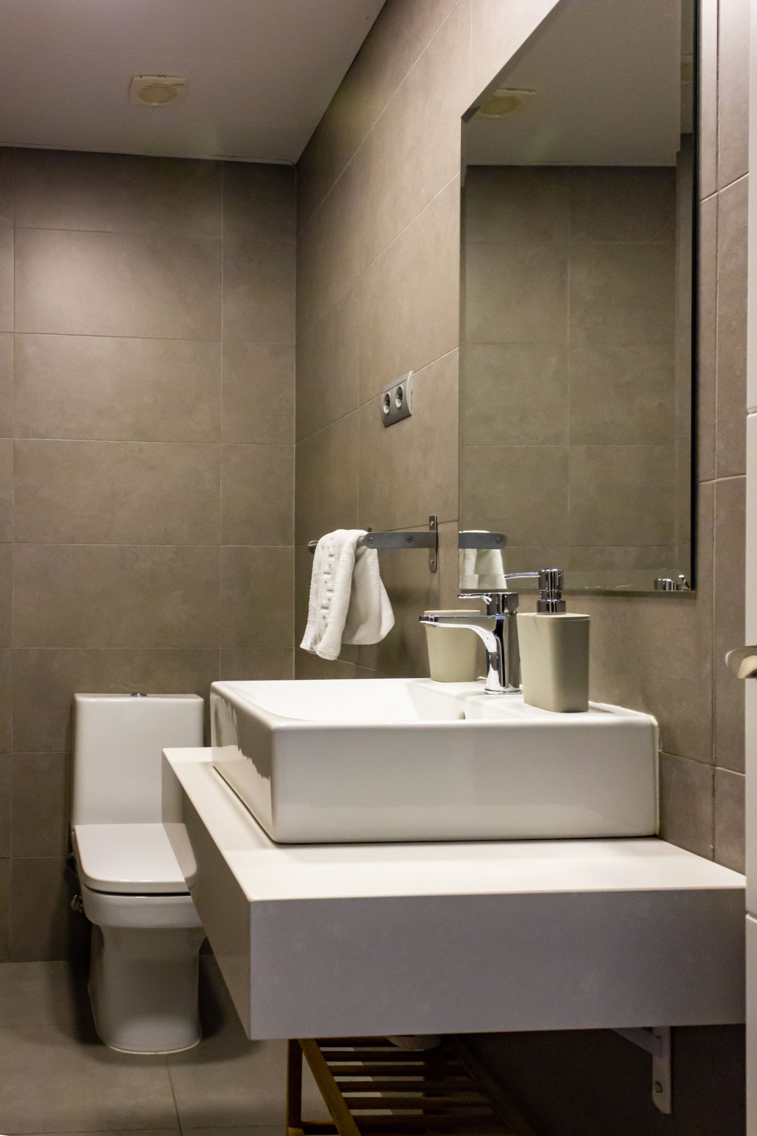 A modern bathroom with a large sink, mirror, and toilet.