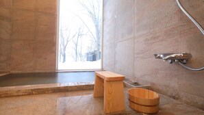 A modern bathroom with a wooden bench, a wooden bucket, and a shower area. - Wakkanupuri (Teshikaga)