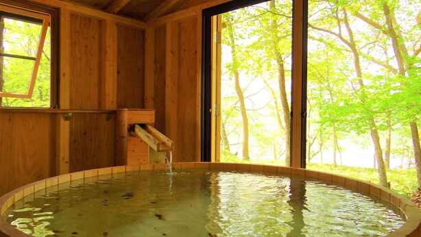 A wooden cabin with a hot tub, large windows, and a wooden ceiling. - Wakkanupuri (Teshikaga)