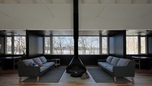 A modern living room with a large fireplace, two sofas, and a view of a snowy landscape through large windows. - Wakkanupuri (Teshikaga)