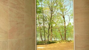 A bathroom with a large window offering a view of a forest and a body of water. - Wakkanupuri (Teshikaga)