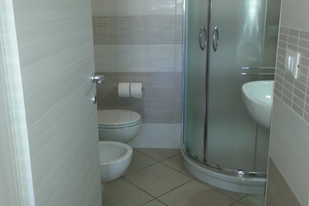 A bathroom with a glass-enclosed shower, a toilet, and a sink.