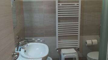 Une salle de bain équipée d’un lavabo, de toilettes et d’un porte-serviettes.